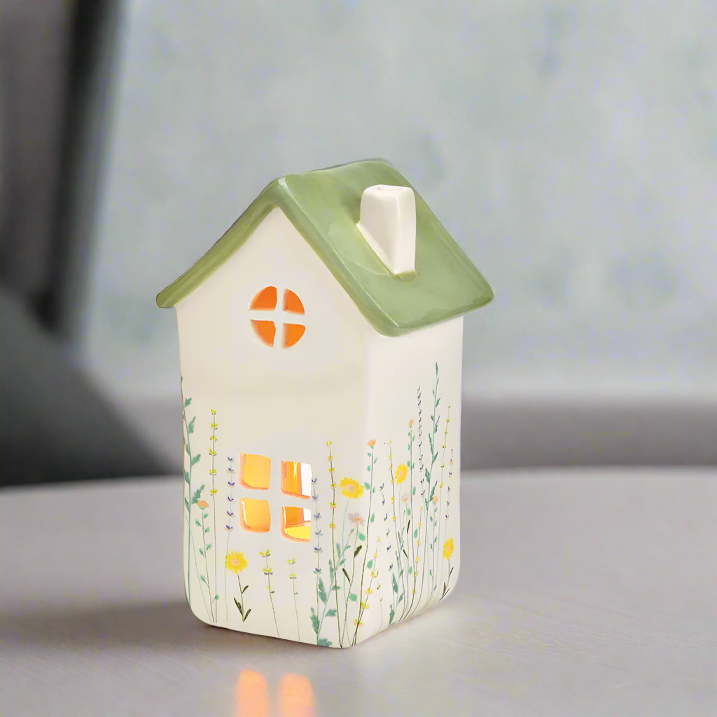 Ceramic house-shaped lantern with a green roof and small window on a white background