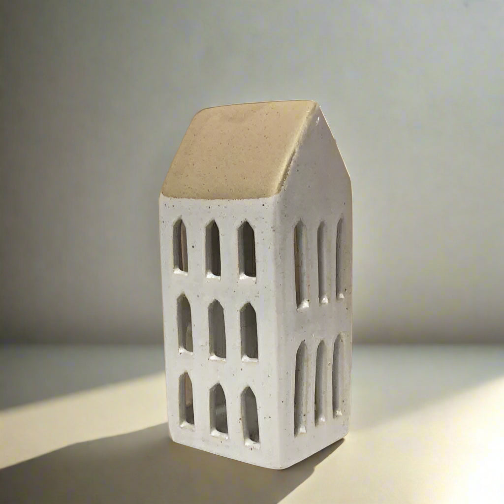 Small ceramic house model with a brown roof on a plain background