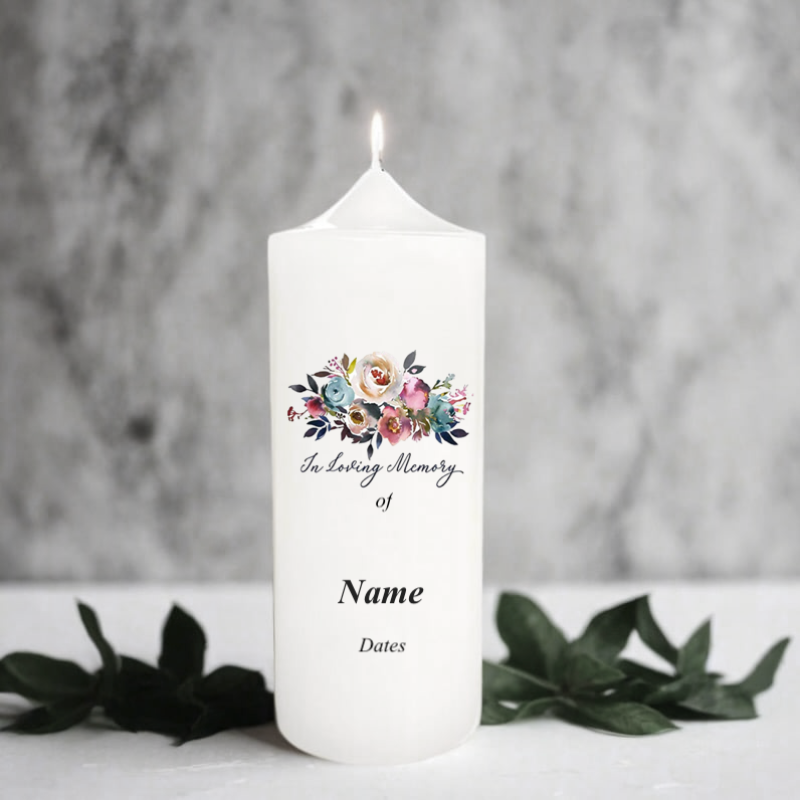 White memorial candle with floral design and text 'In Loving Memory of' on a gray background
