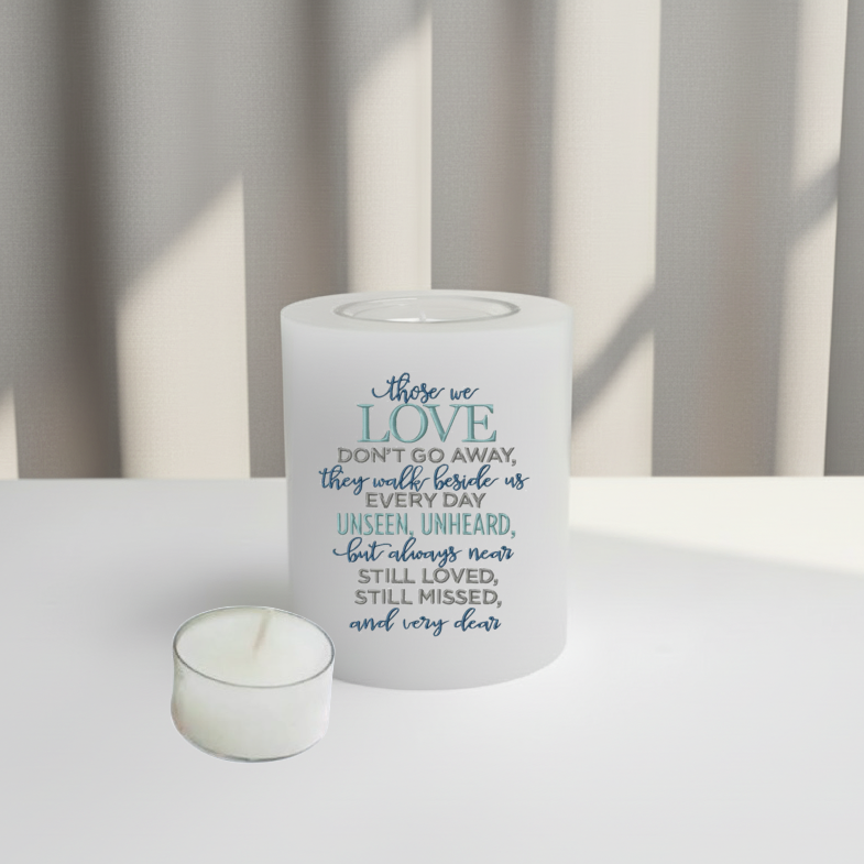 White memorial candle with text on a white surface and curtain background