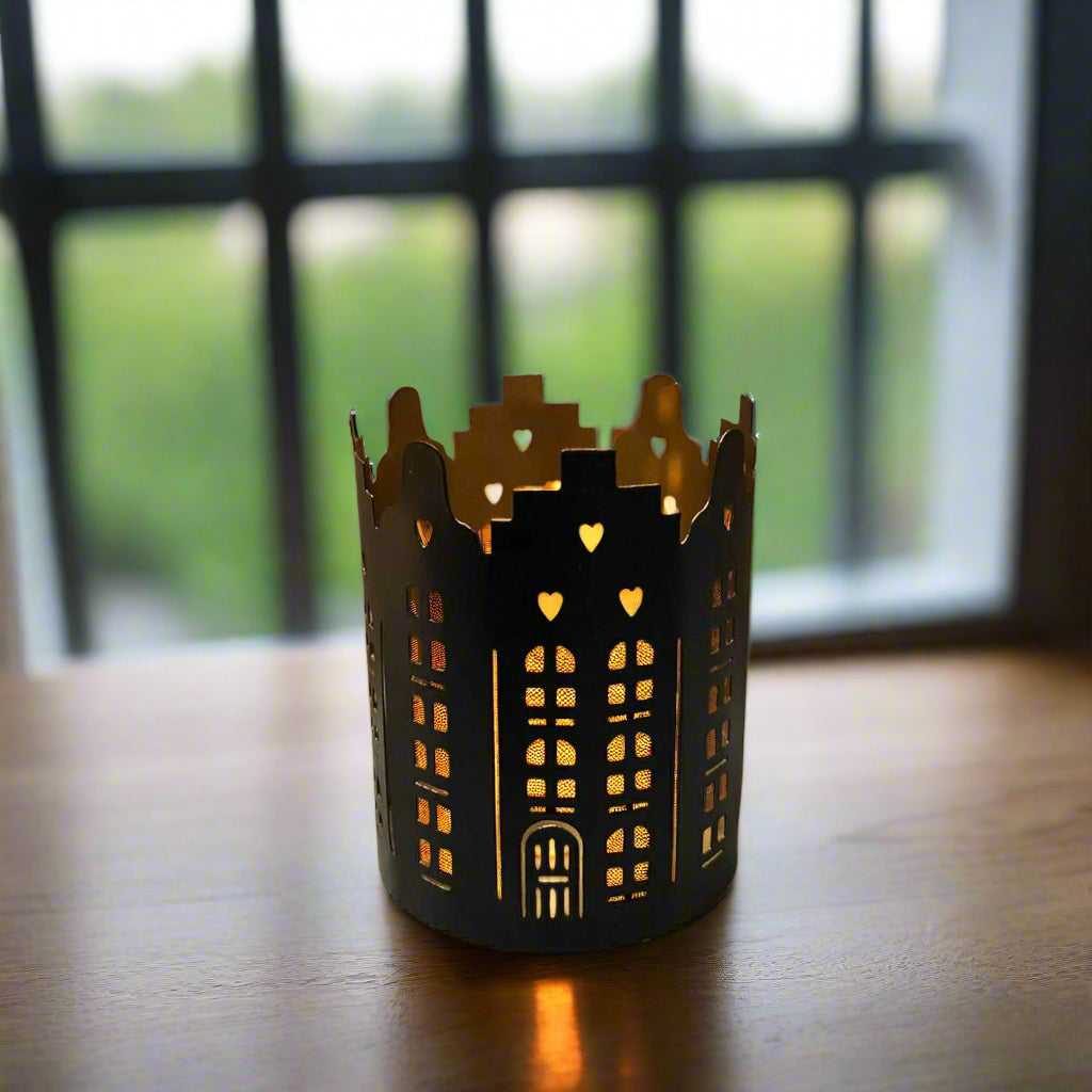 Decorative black candle holder with cut-out patterns on a wooden surface