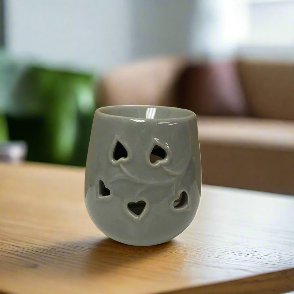 Gray ceramic oil burner with heart shapes on a grey background