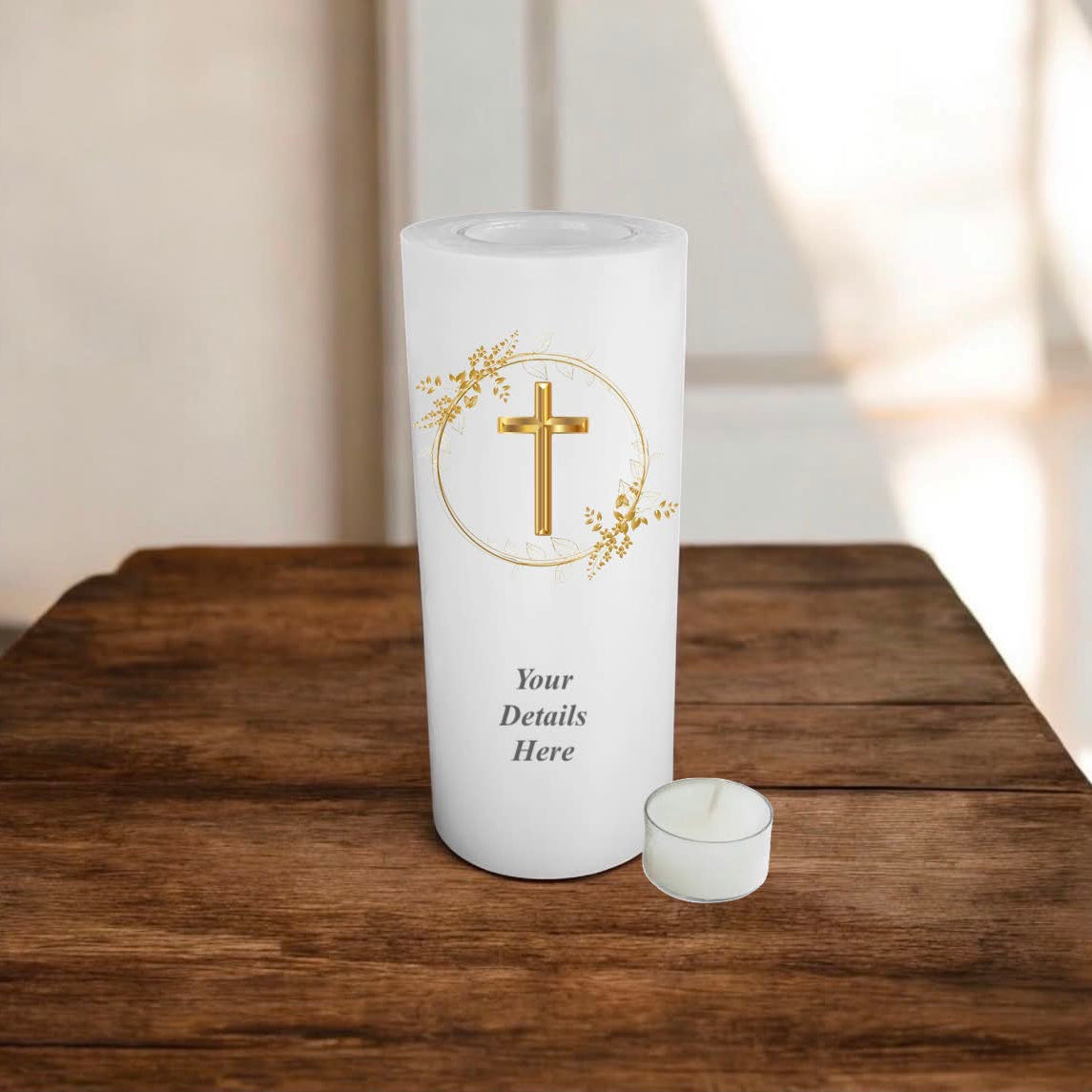 A white candle with gold cross in a wreath design on a wooden surface.