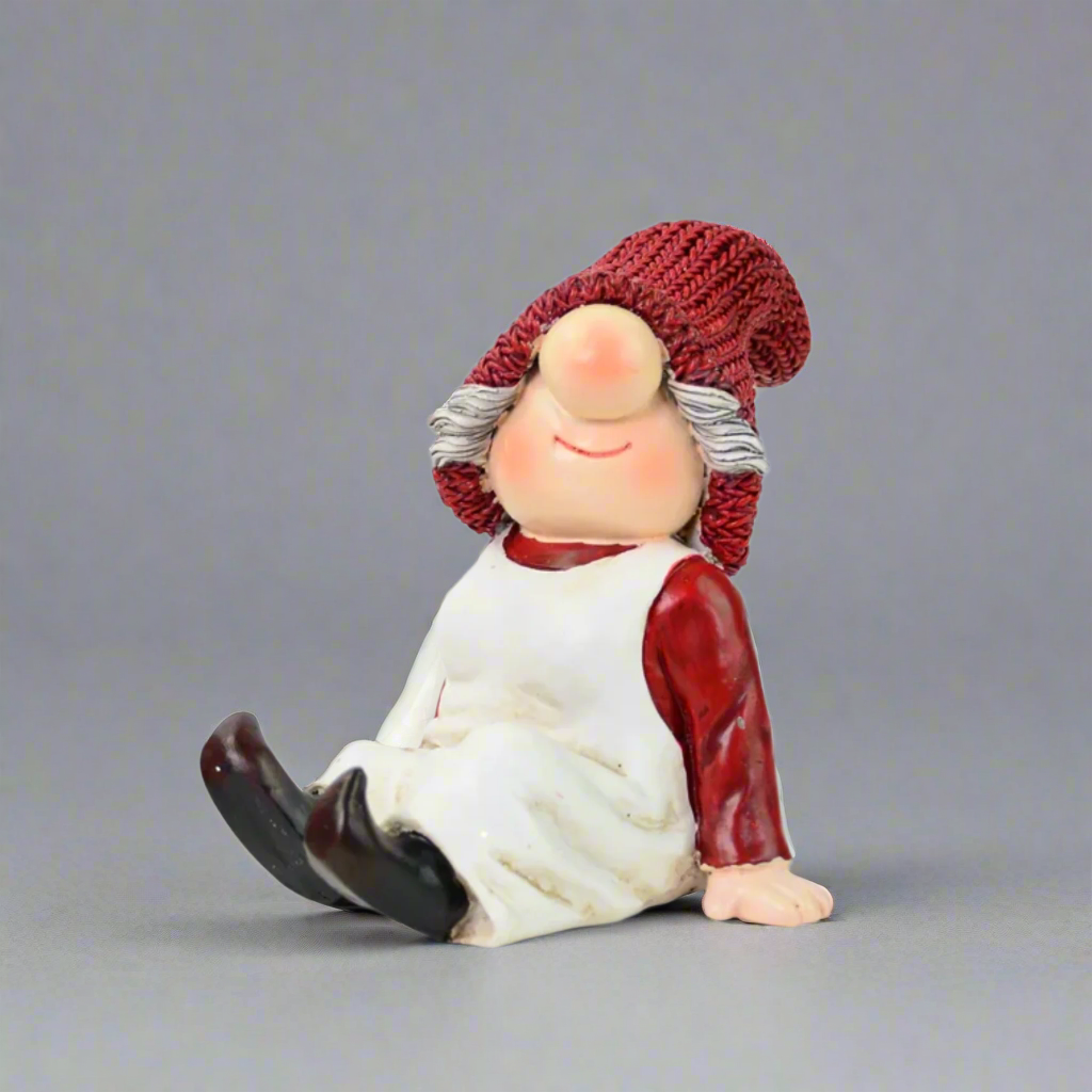 Decorative gnome figurine with a red hat and white apron on a grey background