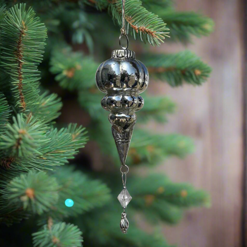 Decorative hanging silver glass ornament on a fir tree