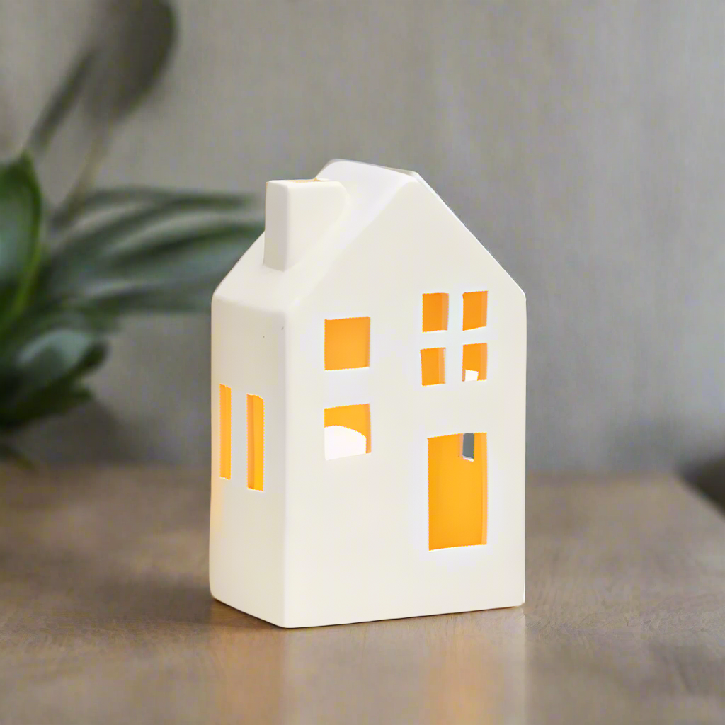 White house-shaped ceramic lantern with tealight inside on a grey background