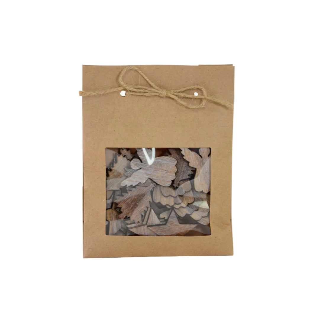 Kraft paper packaging with a window showing wooden scatter decoration pieces, with angels, stars and trees tied with twine on a white background