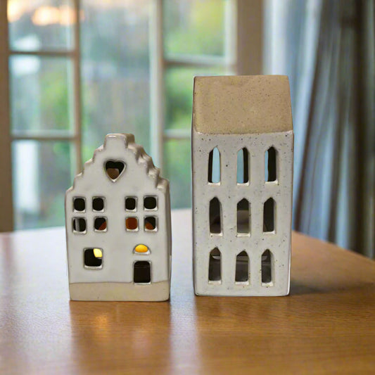 Two ceramic house-shaped lanterns in front of a window
