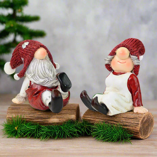 two gnome figurines with red hats sitting on a tree 