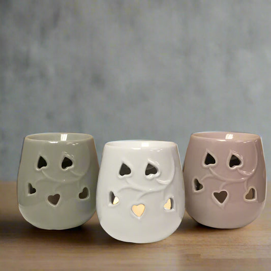 Three ceramic fragrance burner with hearts cut-out designs on a beige background