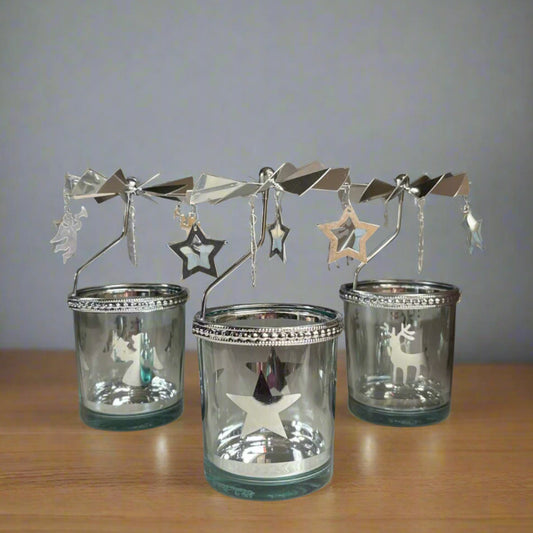 Set of three glass candle holders with decorative metal stands on a wooden surface.