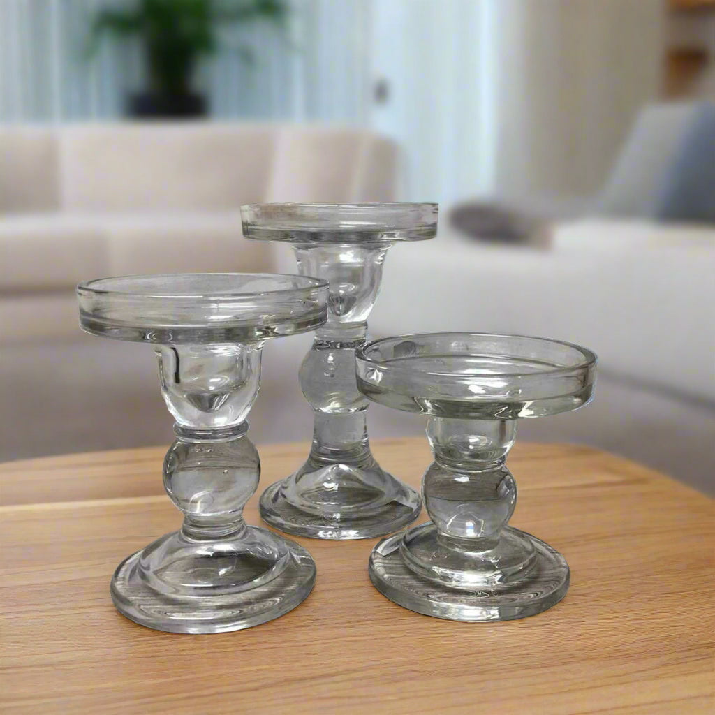 Set of clear glass candle holders on a wooden surface