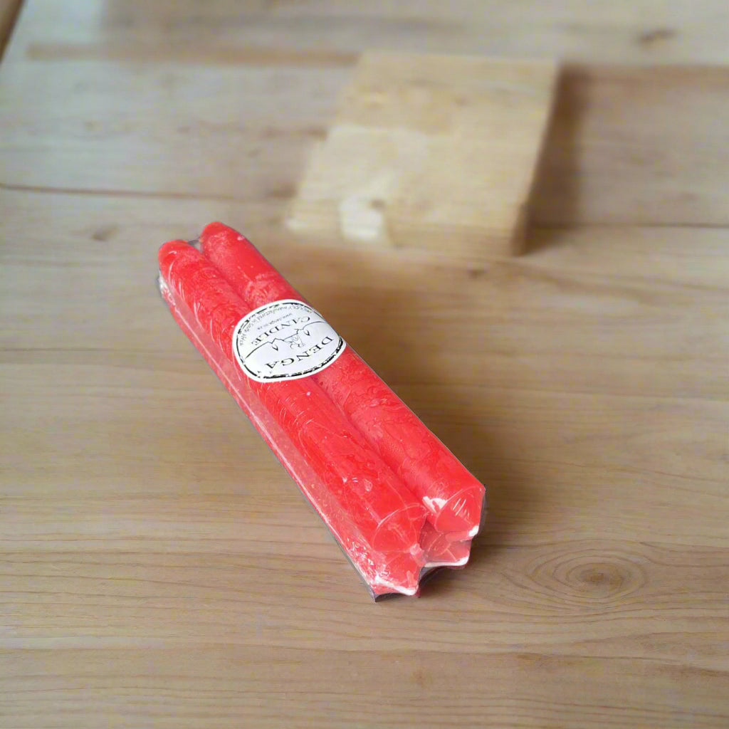 pack of four red dinner candles on a wooden desk