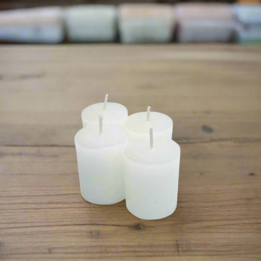 4 white votive candles on a wooden surface