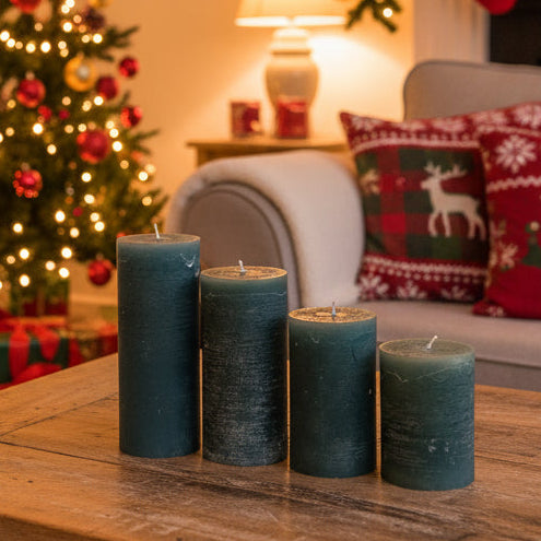 Decorative advent candles on a wooden table with a Christmas tree and stockings in the background