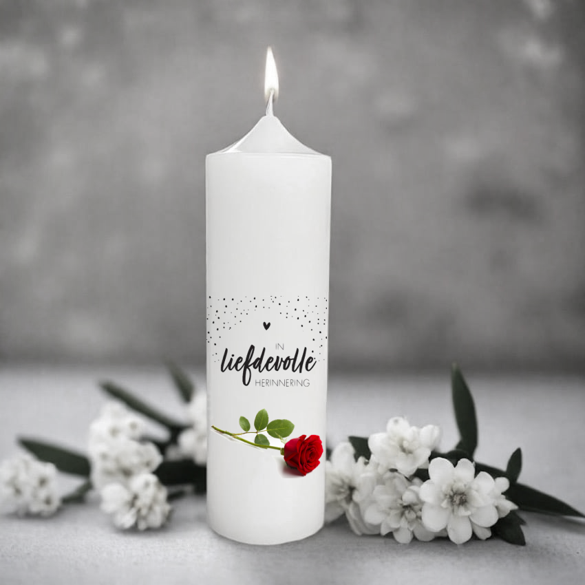 White memory candle with a red rose and afrikaans text on a grey background with flowers