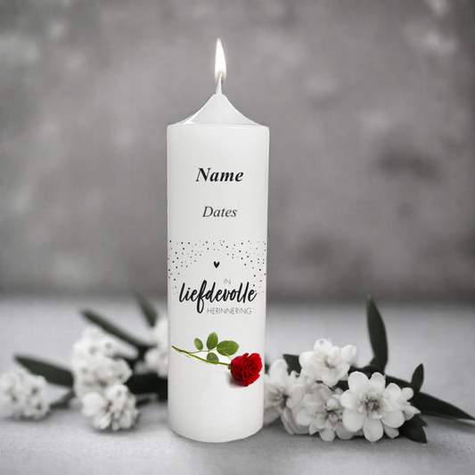 White memory candle with an afrikaans text and a red rose on a grey background with flowers