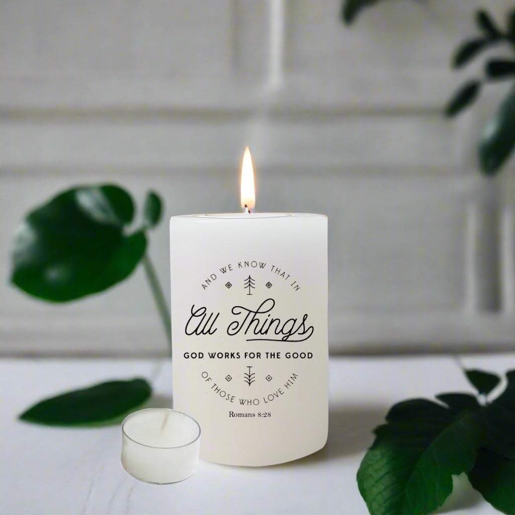 Candle with text design on a white surface with green leaves