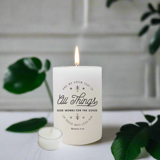Candle with text design on a white surface with green leaves