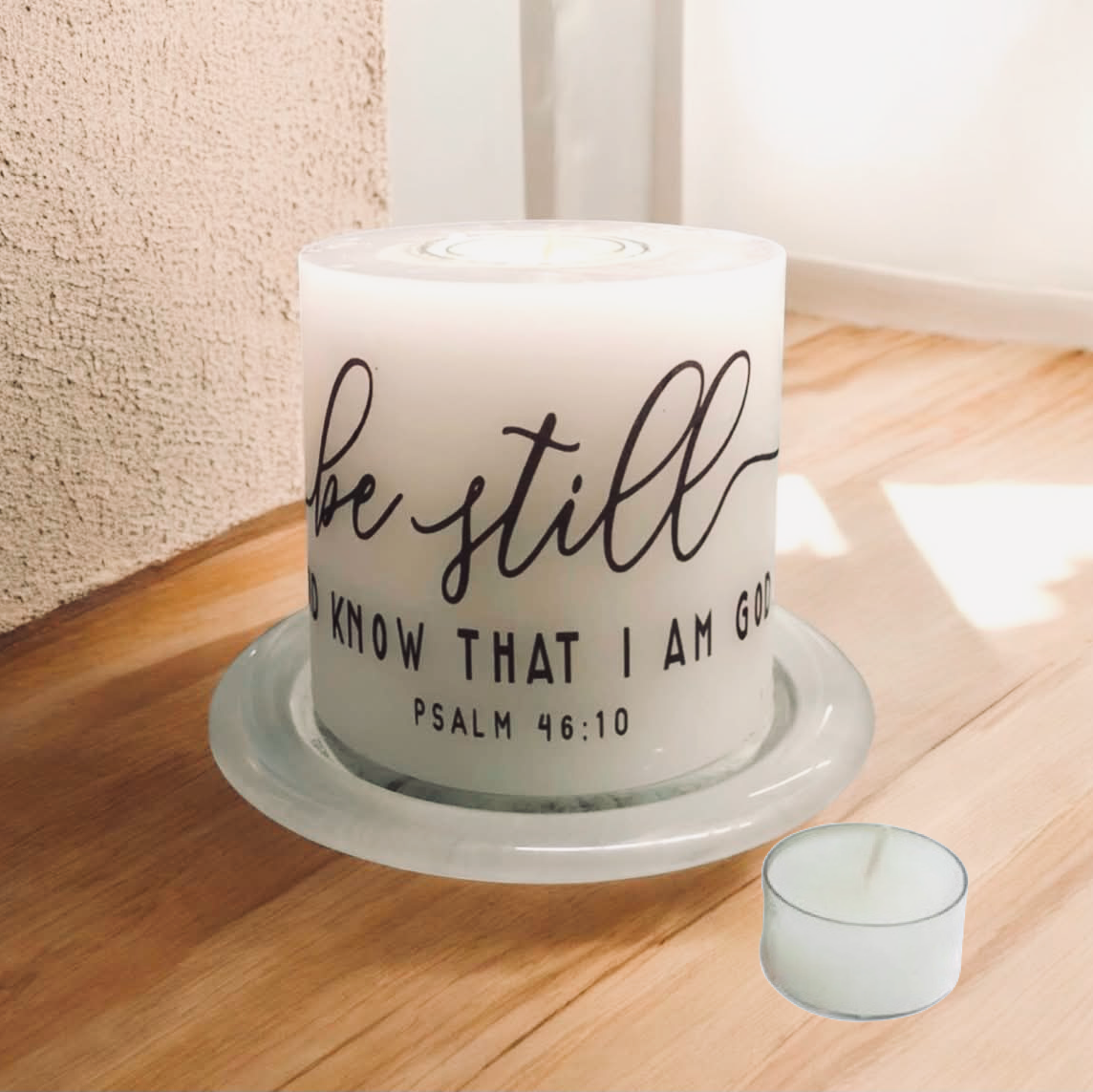 Candle with 'Be still and know that I am God' text on a wooden surface