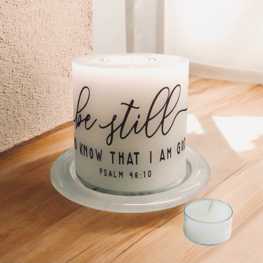 Candle with 'Be still and know that I am God' text on a wooden surface