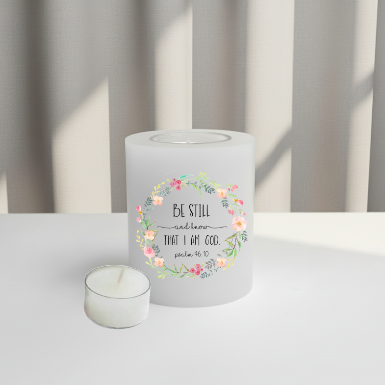 White candle with floral design and text on a white surface.