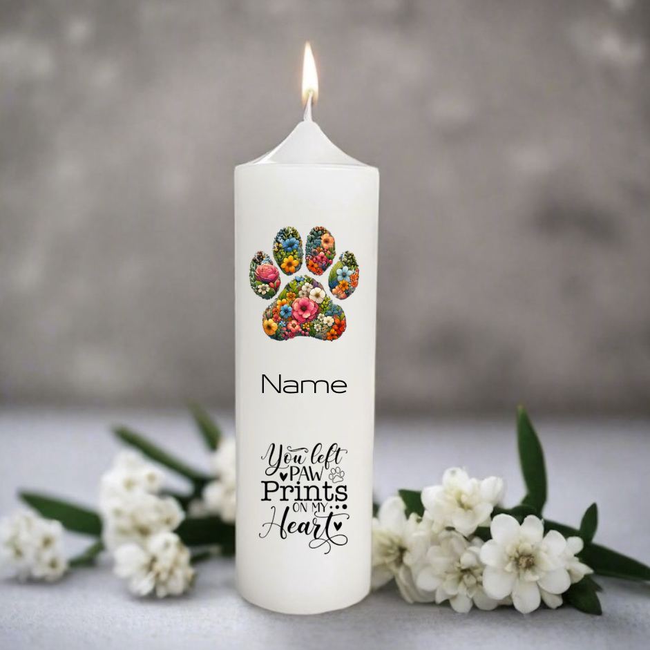 White candle with floral paw print design and text on a gray background