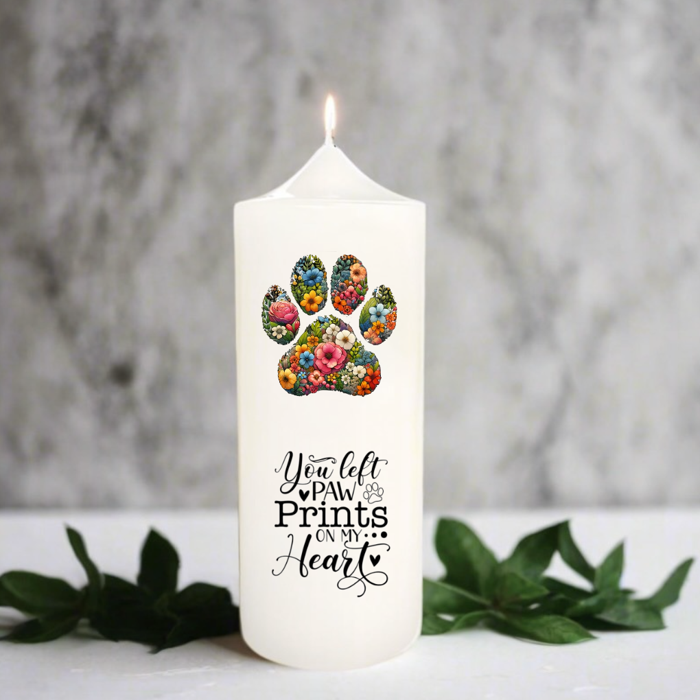 White candle with floral paw print design and text on a gray background