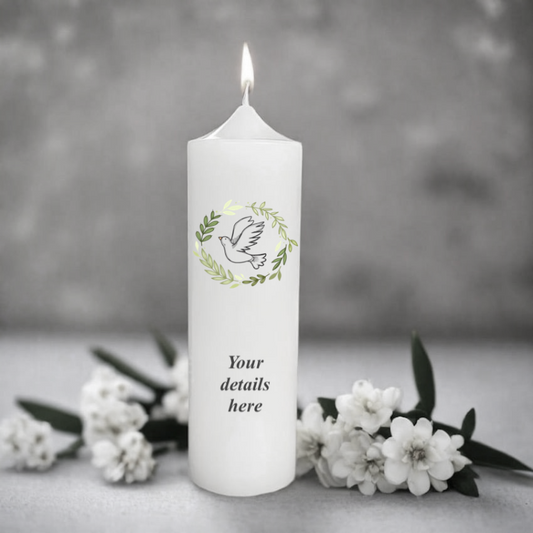 White christening or confirmation candle with a dove design and floral wreath, surrounded by white flowers on a gray background
