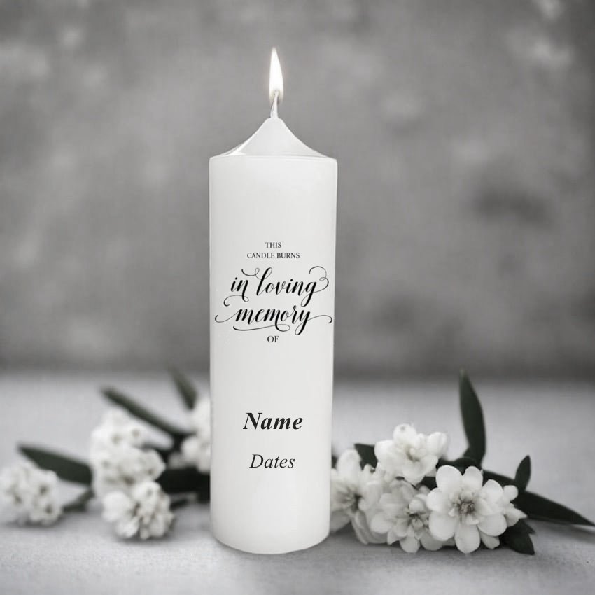 White candle with 'In Loving Memory' text and floral design, surrounded by white flowers on a grey background.