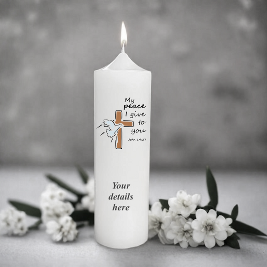 White candle with religious design and text on a gray background with flowers.