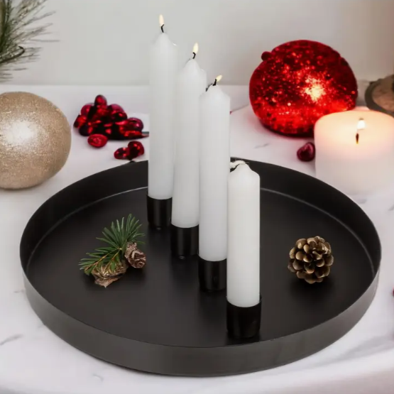 Decorative setup with candles, pine cones, and Christmas balls on a black tray.