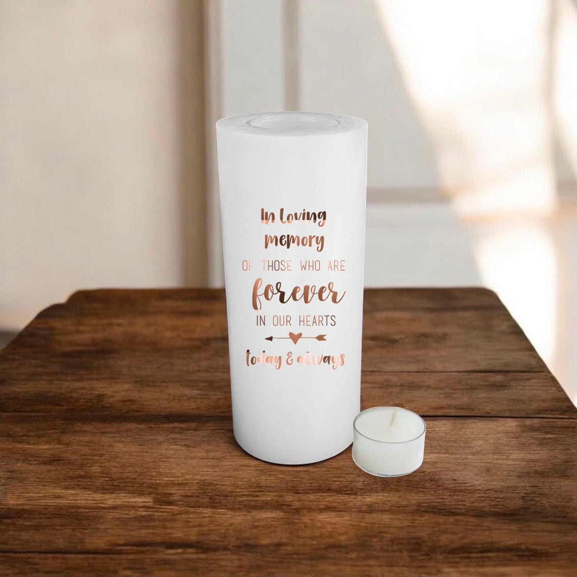white candle with brown memorial text, placed on a wooden surface.