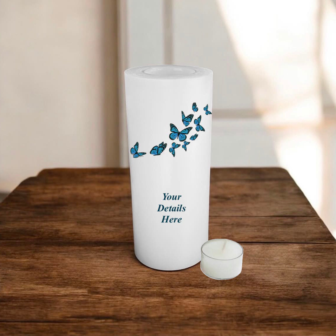 White candle with blue butterfly design on a wooden surface