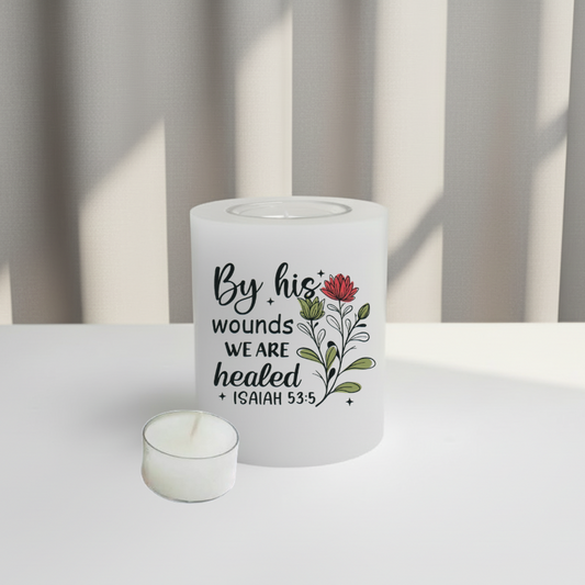 A white candle with a printed quote and floral illustration, sitting on a white surface.