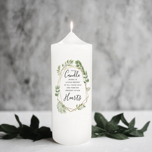 White memory candle with greenery design and text on a gray background