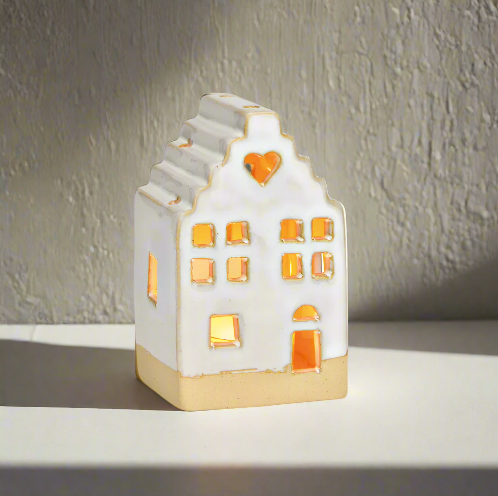 Ceramic house-shaped lamp with a heart window on a cement wall background