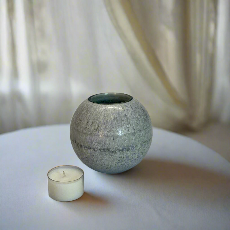 A grey crystal wax ball candle with a built-in glass holder to place a tealight or flameless LED tealight 
