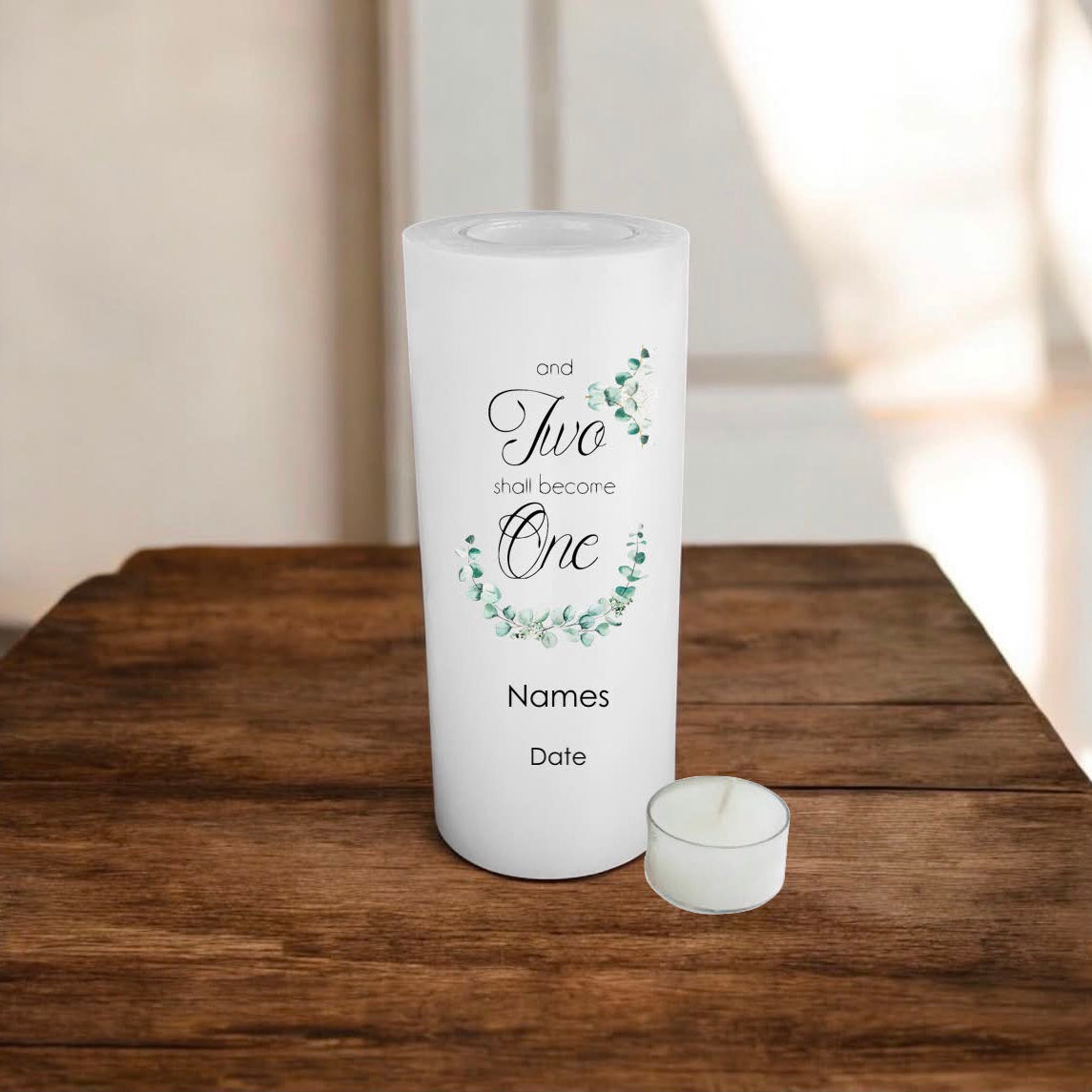 A white candle with eucalyptus design and the text 'and Two shall become One' sits on a rustic wooden table.
