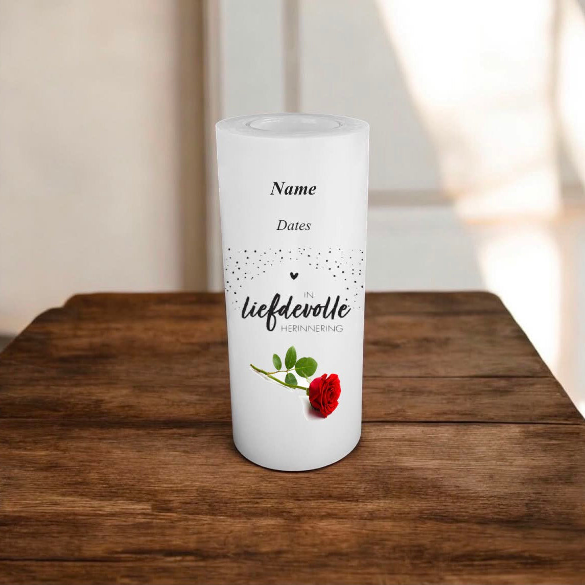 A white candle standing on a wooden table, printed in Afrikaans, and a red rose with green leaves.