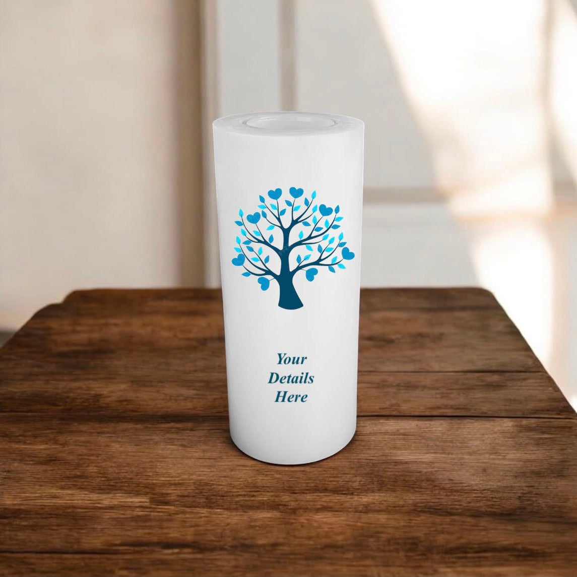 White candle with blue tree design and 'Your Details Here' text on a wooden surface.