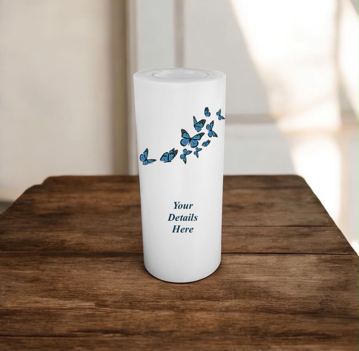White candle with blue butterfly design on a wooden surface