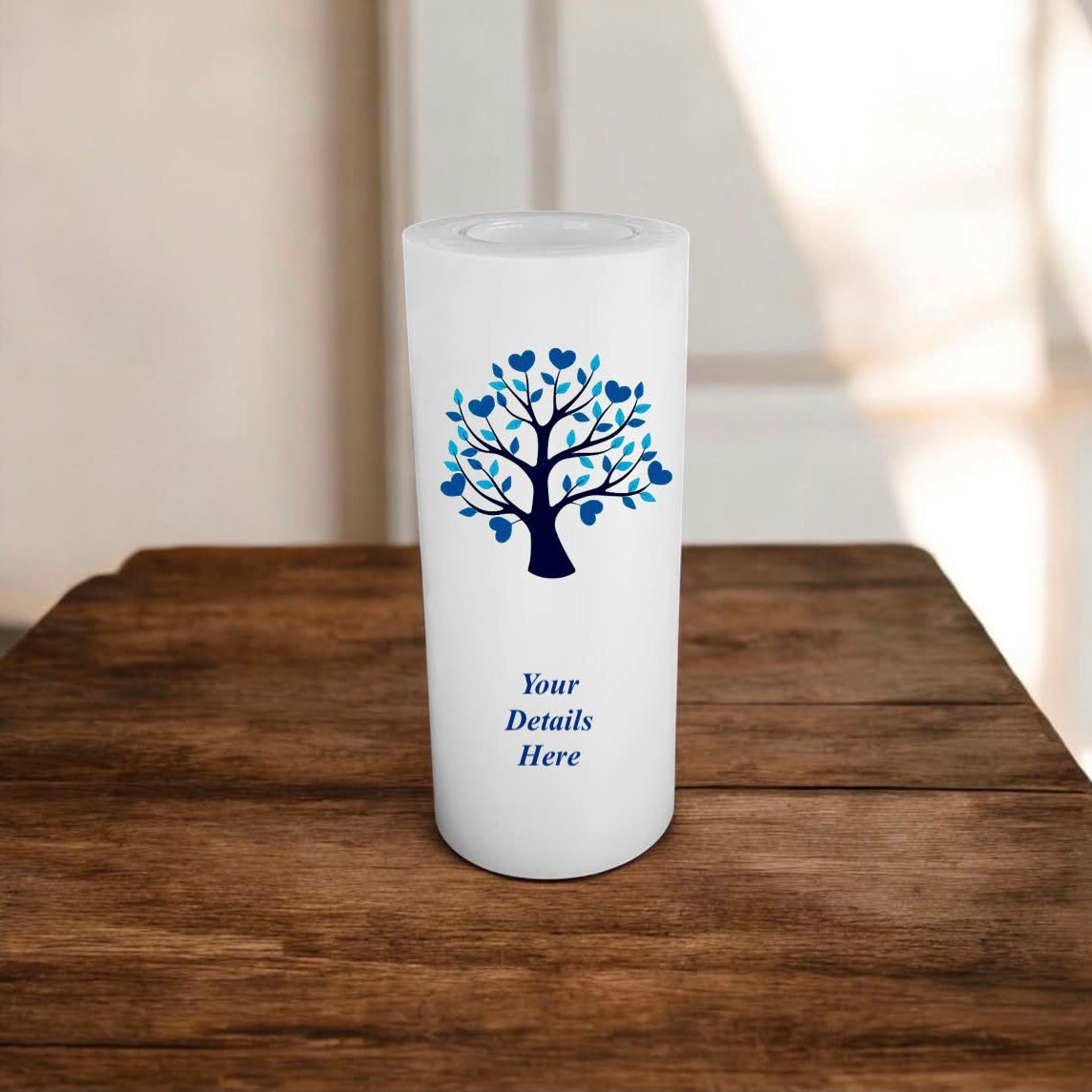 White candle with blue tree design and 'Your Details Here' text on a wooden surface.