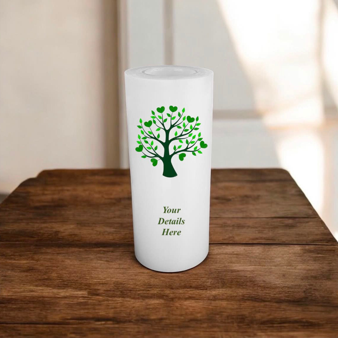 White candle with a green tree design on a wooden surface
