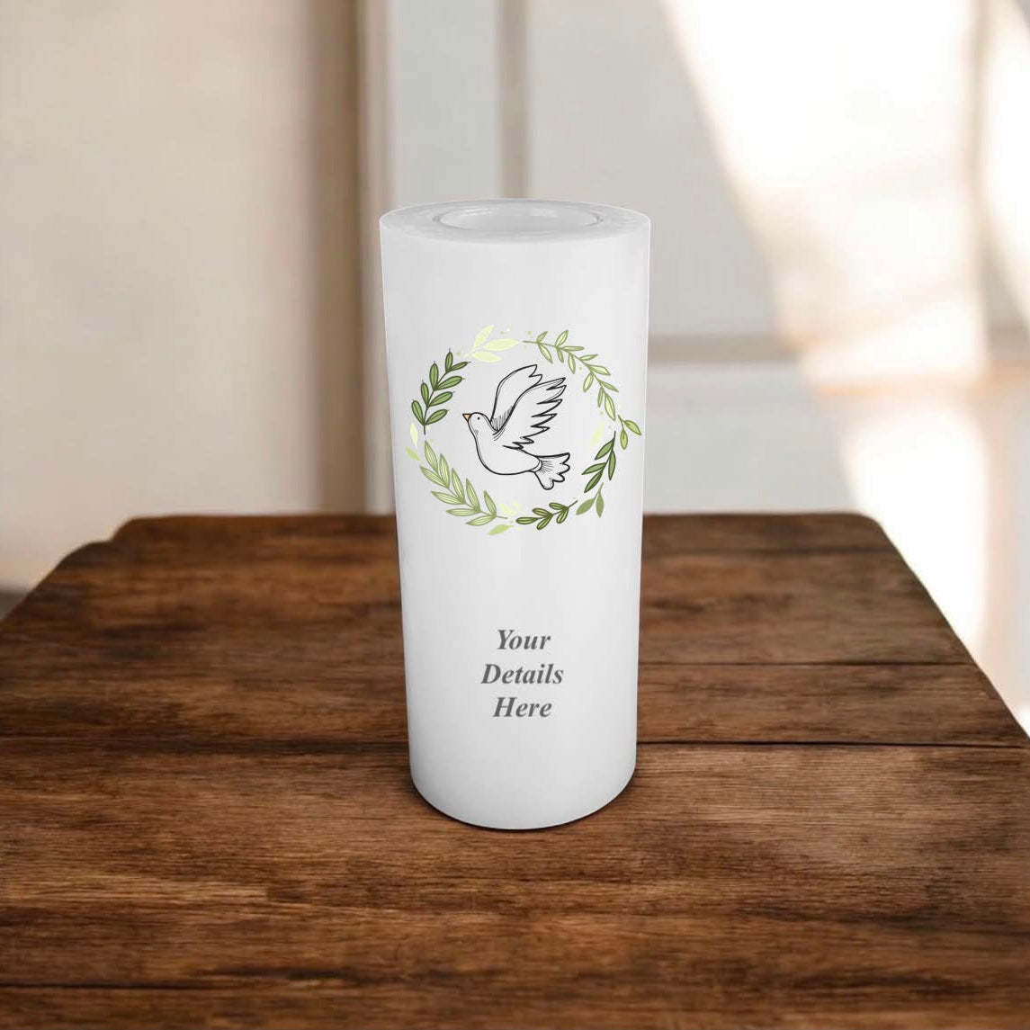 White candle with a bird in wreath design on a wooden surface