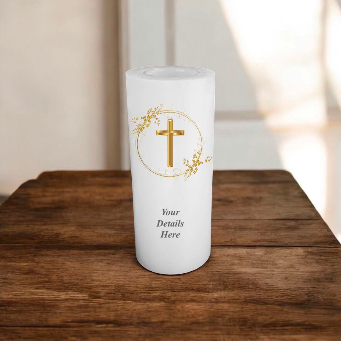 A white candle with gold cross in a wreath design on a wooden surface.