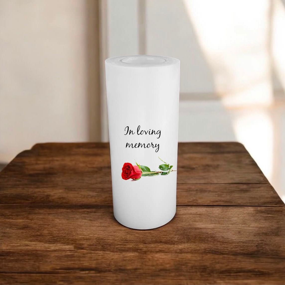 white candle printed with text and a rose on a wooden surface.