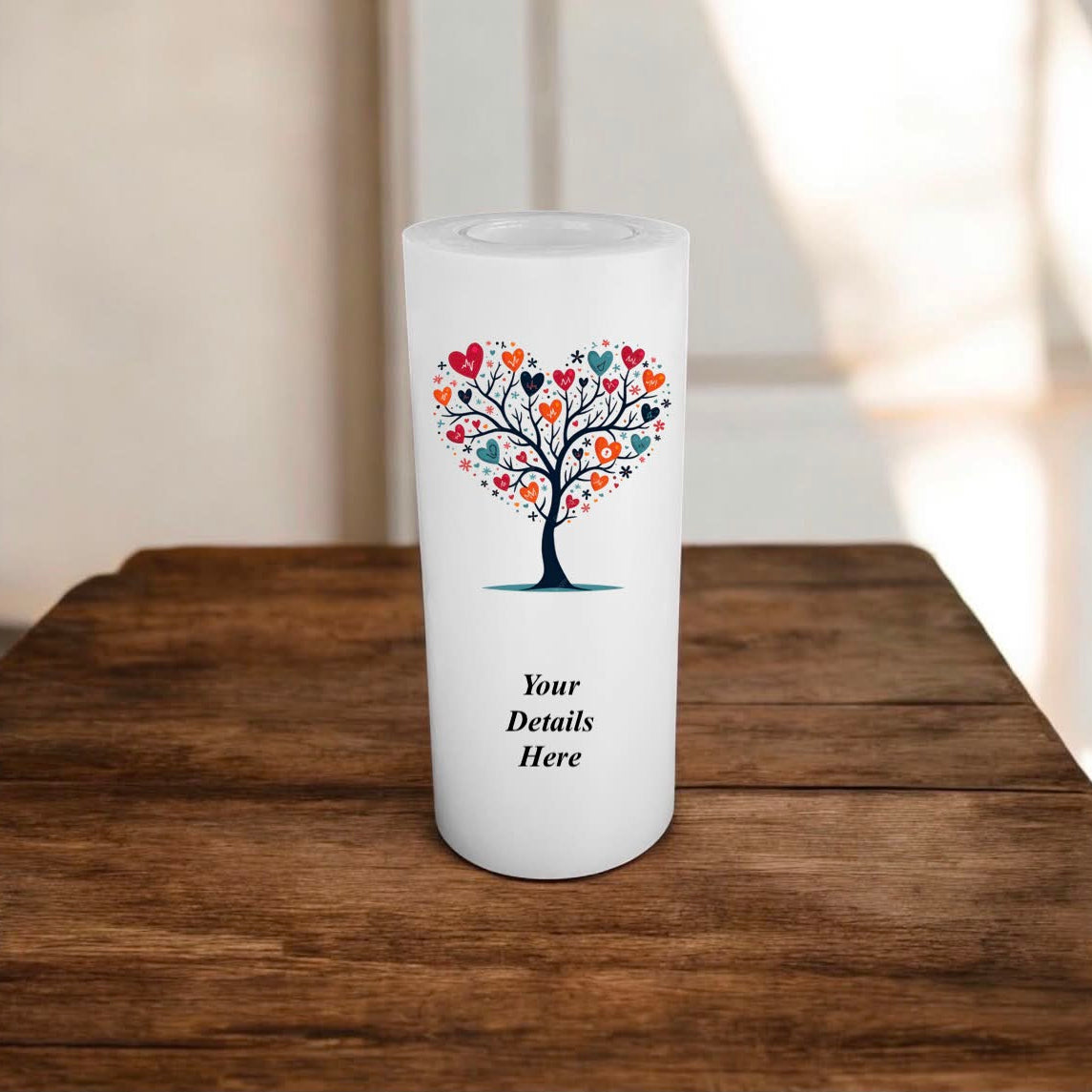 White candle with a decorative tree design on a wooden surface