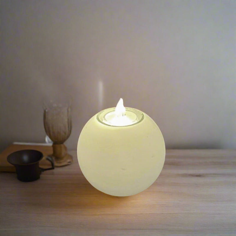A white ball candle with a built-in glass holder to place a tealight or a flameless LED tealight.