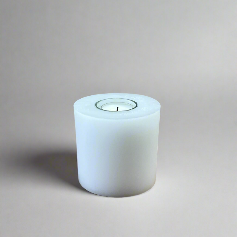 A white pillar candle with a built-in glass holder to place a tealight or a flameless LED tealight.